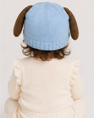 Child wearing a blue knitted hat with dog ears on a light background