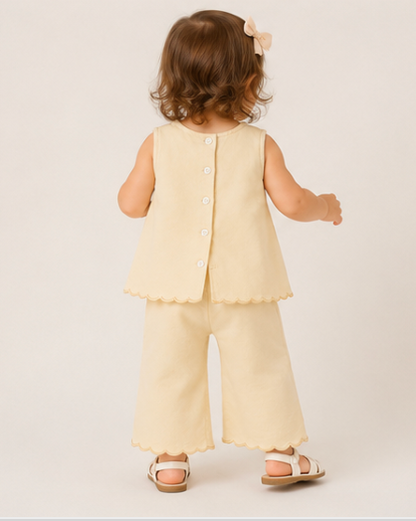Child wearing a light yellow outfit with a plain background