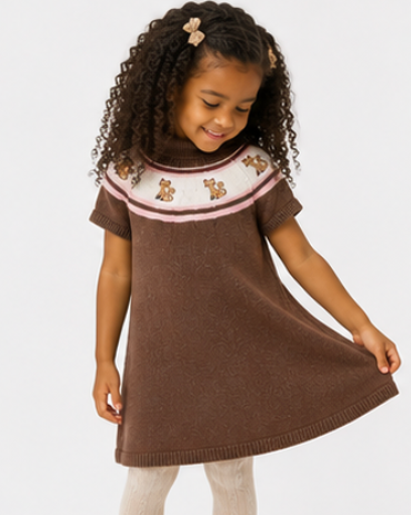 Young girl wearing a brown dress with embroidered details on a white background