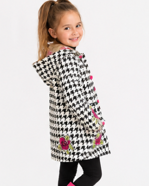 Young girl wearing a houndstooth-patterned coat with floral details and pink rain boots on a white background