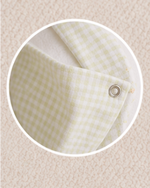Close-up of a green checkered fabric with a metal ring on a beige background