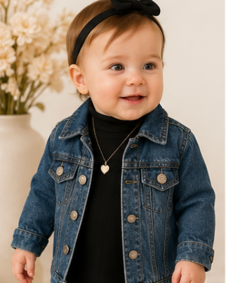 Baby wearing a denim jacket and black headband with a neutral background