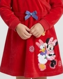 A close-up of a red plush long-sleeve dress with a blue bow at the waist and Minnie Mouse and Daisy Duck embroidered on the front, worn by a child whose hands and lower body are visible.