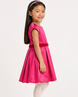 Young girl wearing a pink dress with a belt on a white background