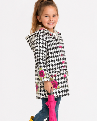 Young girl wearing a houndstooth-patterned coat with floral accents, yellow boots, and holding a pink umbrella on a white background.