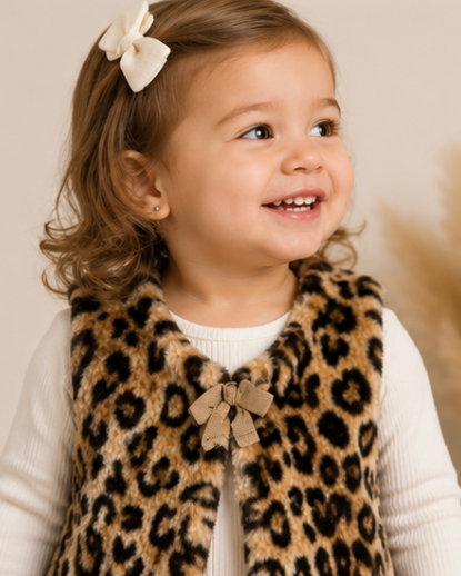 Child wearing a leopard print vest with a bow tie, smiling against a neutral background