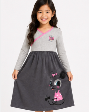 A young girl modeling a long-sleeve dress with a light gray top, a dark gray skirt, and a pink and black cartoon mouse graphic on the front, set against a plain white studio background.